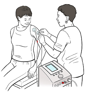 Technician placing electrodes attached to TENS machine on woman's arm.