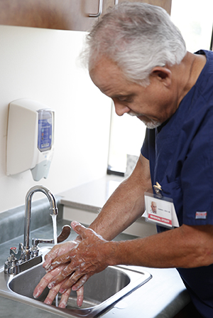 Proveedor de atención médica lavándose las manos en un lavabo.